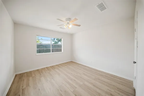 an empty room with a window and a ceiling fan