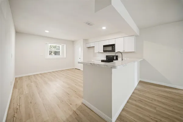 a view of a kitchen with wooden floor and electronic appliances