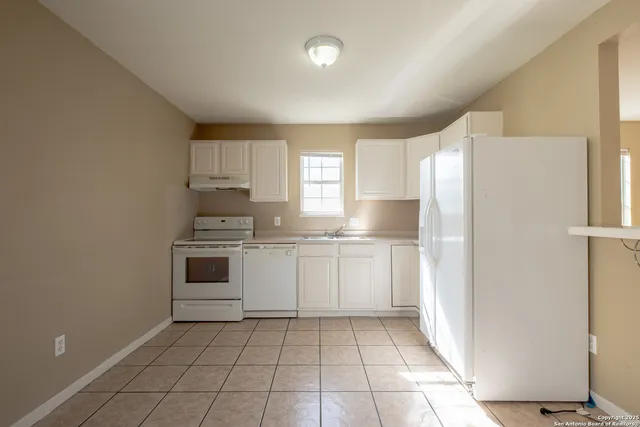 a kitchen with a refrigerator a stove top oven and cabinets