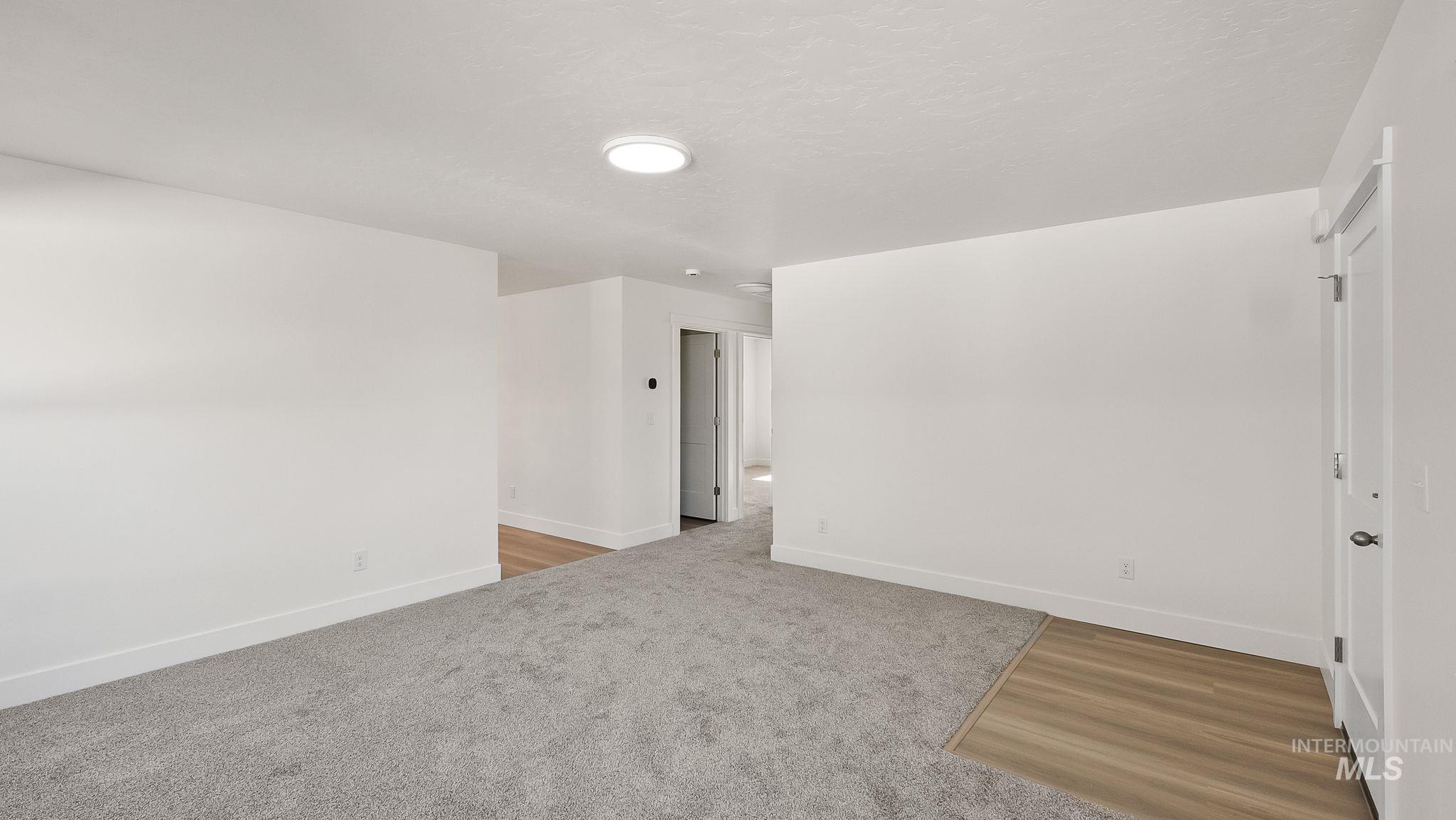 1440 Castle Way Emmett, ID 83617 - Photo 7 of 30 Empty room featuring light colored carpet and a textured ceiling