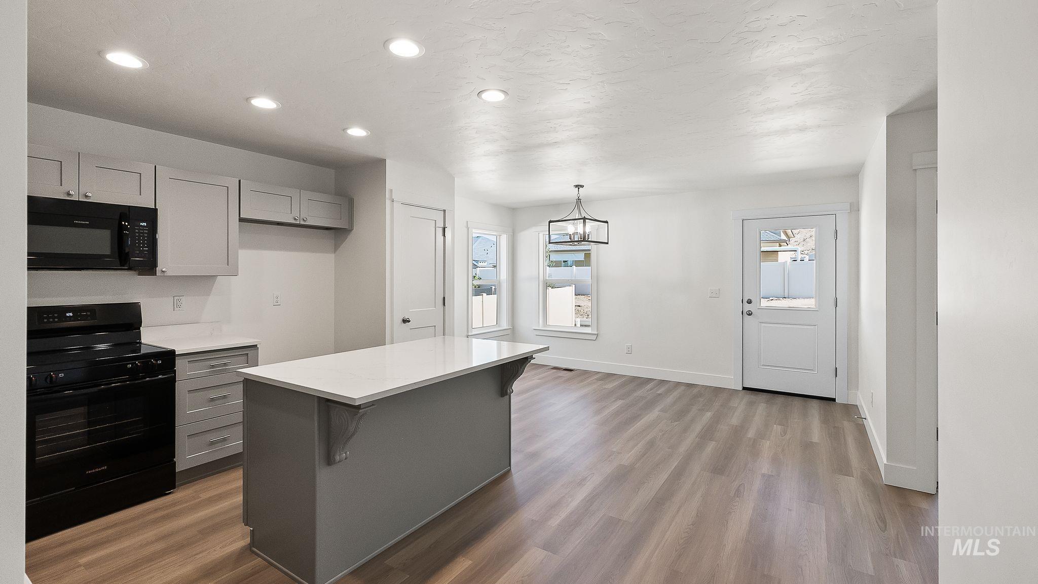 1440 Castle Way Emmett, ID 83617 - Photo 8 of 30 Kitchen with gray cabinets, black appliances, recessed lighting, a kitchen bar, and dark wood-type flooring