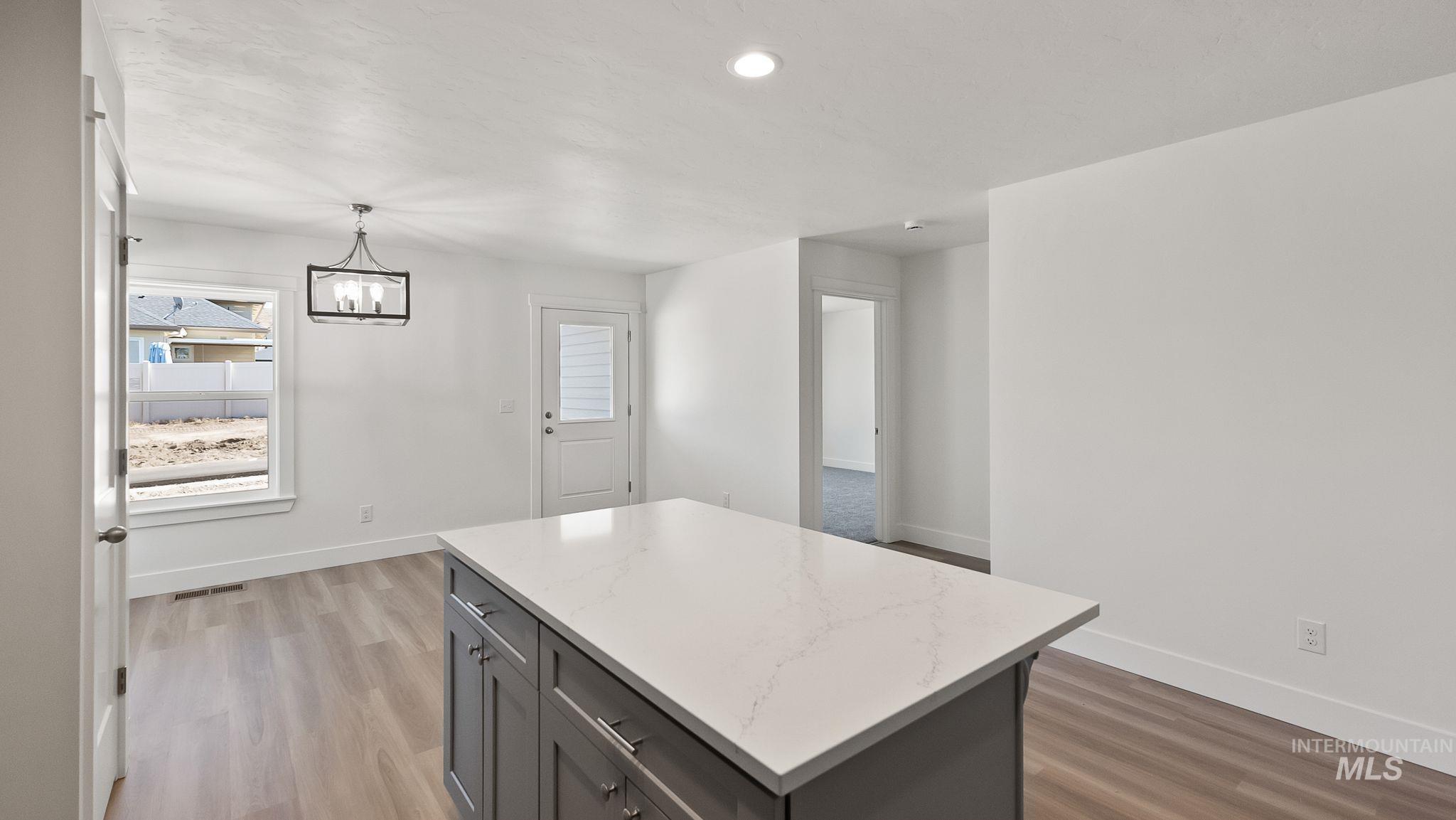 1440 Castle Way Emmett, ID 83617 - Photo 9 of 30 Kitchen with pendant lighting, a chandelier, a kitchen island, light wood-type flooring, and recessed lighting