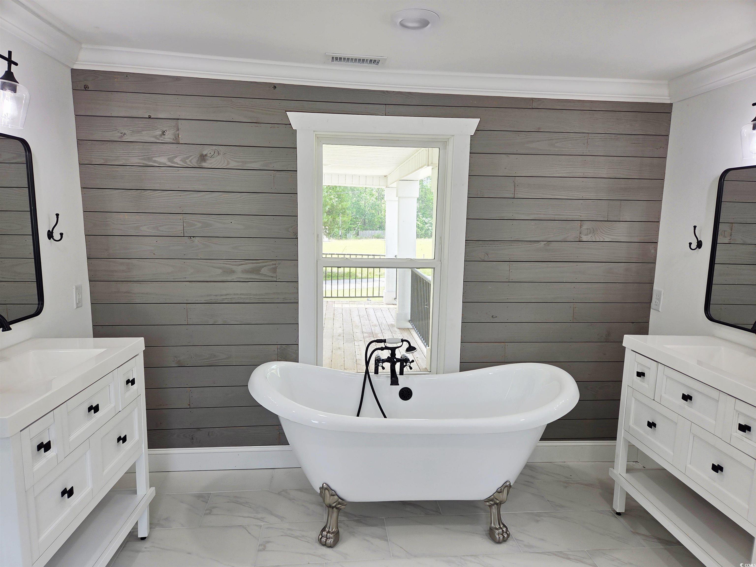 675 Liberty Church Road Loris, SC 29569 - Photo 31 of 35 Full bath featuring a sink, two vanities, a freestanding tub, wooden walls, and marble finish floor