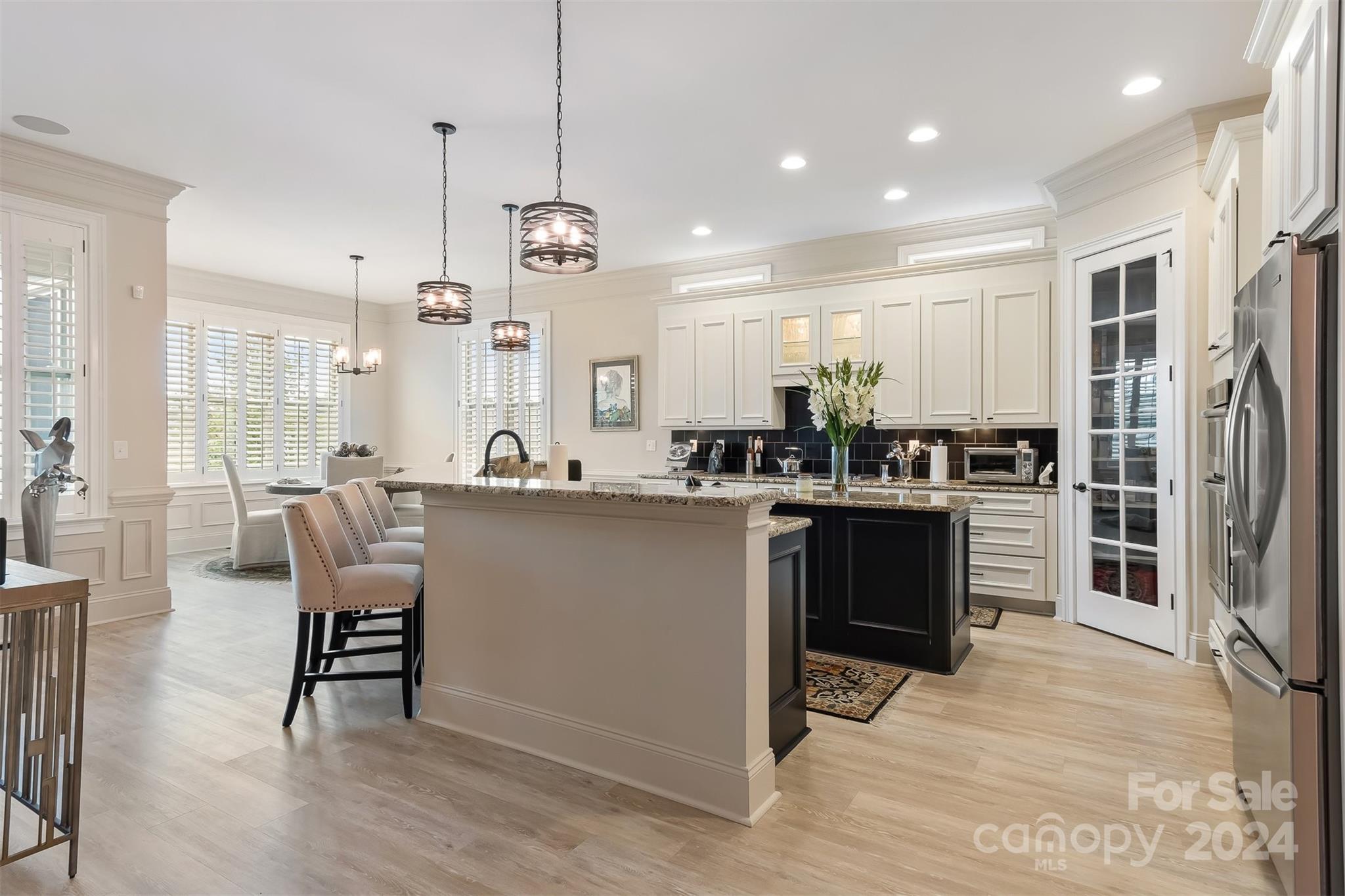 15608 Lake Ridge Road Charlotte, NC 28278 - Photo 8 of 37 a kitchen with stainless steel appliances kitchen island granite countertop a refrigerator a stove a sink a dining table and chairs with wooden floor