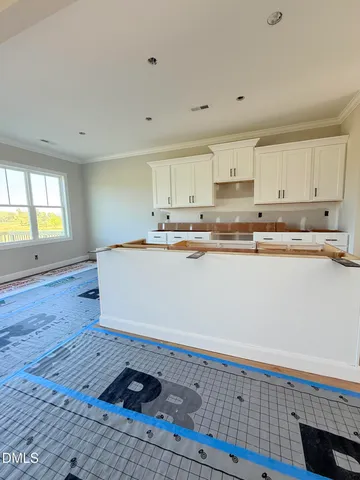 a large white kitchen with wooden floors and stainless steel appliances