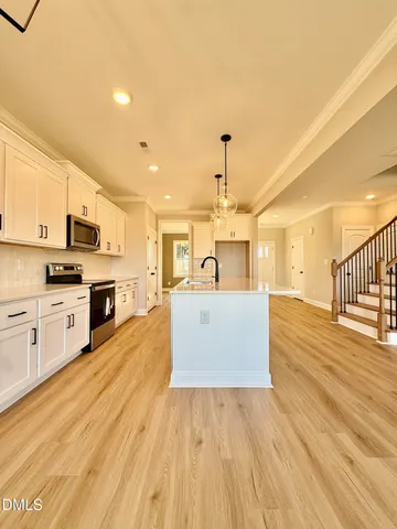 a view of a kitchen with kitchen island a sink wooden floor and stainless steel appliances