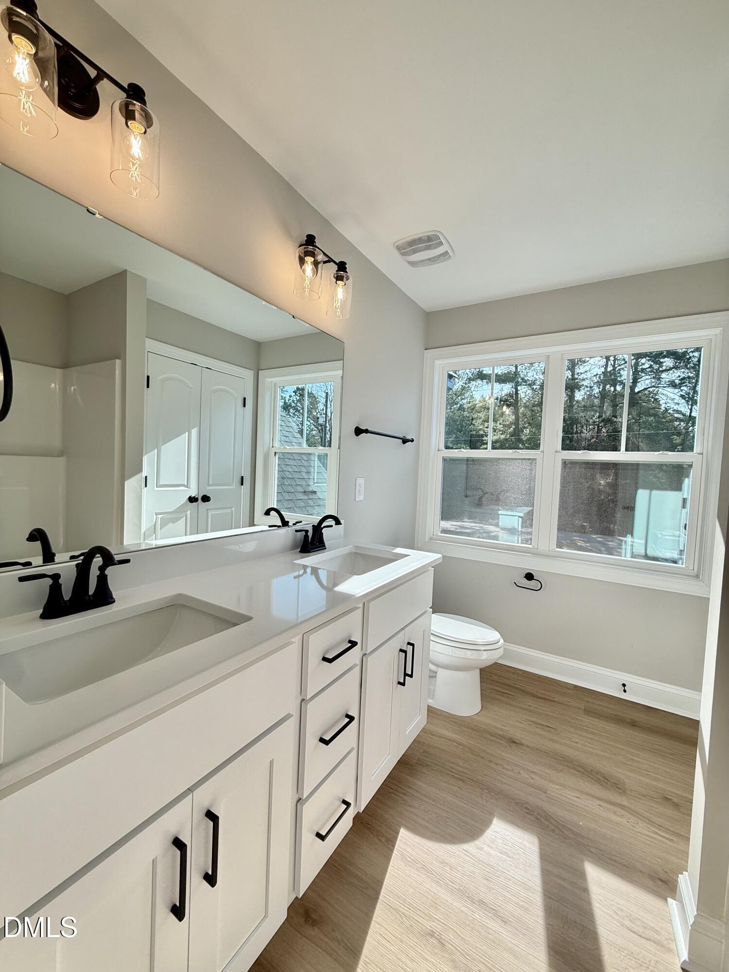 6862 Fire Tower Road Spring Hope, NC 27882 - Photo 25 of 35 a bathroom with a double vanity sink a toilet a mirror and window