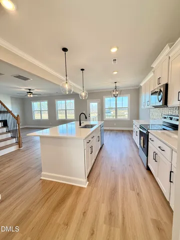 a large kitchen with stainless steel appliances granite countertop a lot of counter space and wooden floors