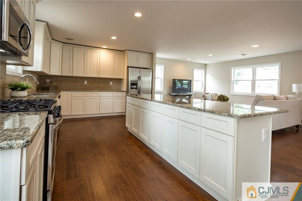 44 Caldwell Road Edison, NJ 08817 - Photo 12 of 25 a kitchen with stainless steel appliances kitchen island granite countertop a sink cabinets and wooden floor