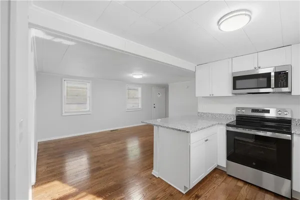 a kitchen with granite countertop a stove top oven a sink dishwasher and a microwave oven with wooden floor