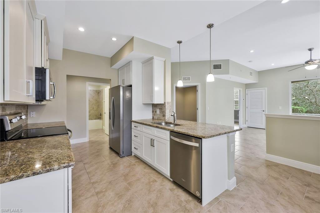 18225 Creekside Preserve Loop, Unit 102 Fort Myers, FL 33908 - Photo 11 of 25 Kitchen featuring white cabinetry, dark stone counters, appliances with stainless steel finishes, decorative light fixtures, and a peninsula