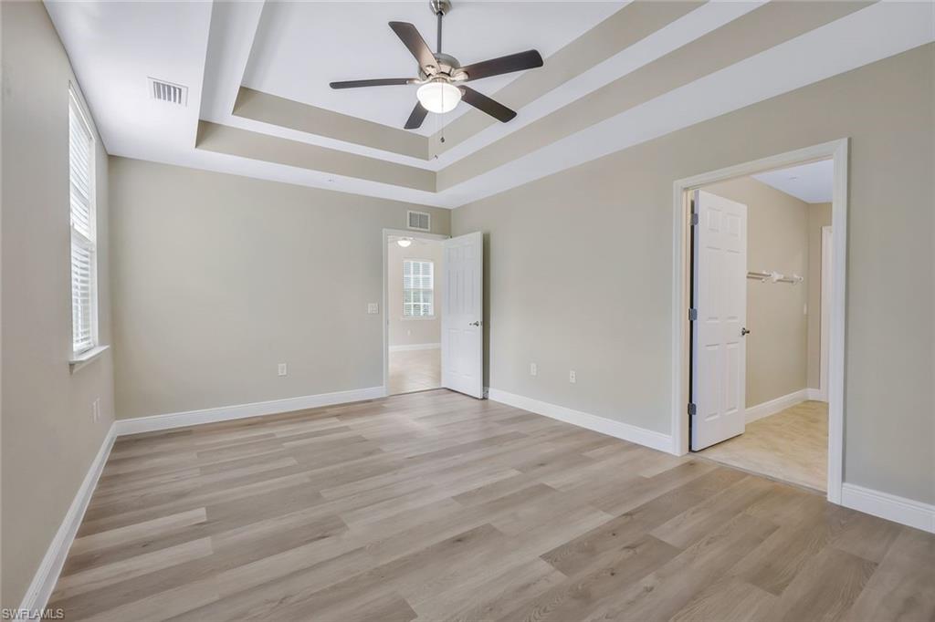 18225 Creekside Preserve Loop, Unit 102 Fort Myers, FL 33908 - Photo 15 of 25 Unfurnished bedroom featuring a raised ceiling, light wood-type flooring, a ceiling fan, a spacious closet, and multiple windows