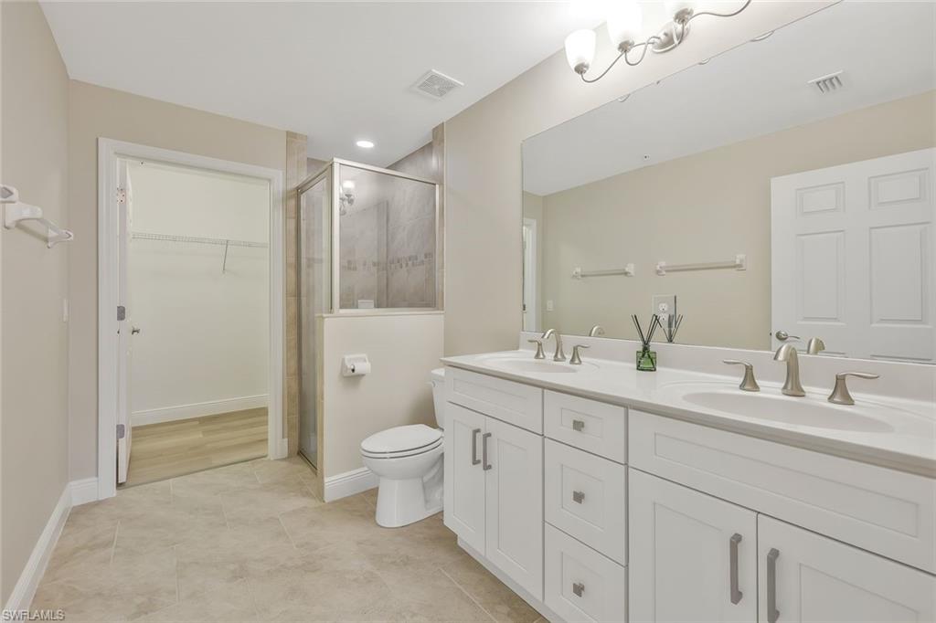 18225 Creekside Preserve Loop, Unit 102 Fort Myers, FL 33908 - Photo 17 of 25 Full bath with a walk in closet, double vanity, a stall shower, light tile patterned floors, and recessed lighting