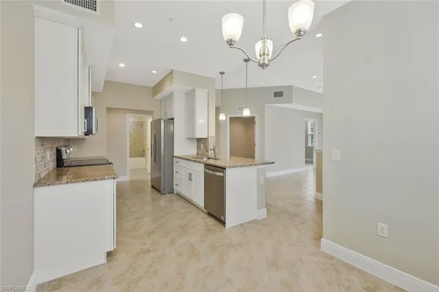 a kitchen with granite countertop a sink a counter top space appliances and cabinets