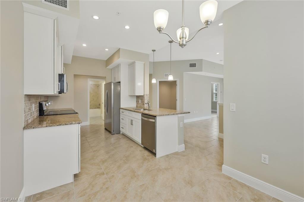 18225 Creekside Preserve Loop, Unit 102 Fort Myers, FL 33908 - Photo 8 of 25 Kitchen featuring light stone counters, white cabinets, a chandelier, decorative backsplash, and recessed lighting