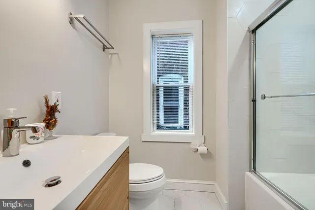 a bathroom with a glass shower door and a window