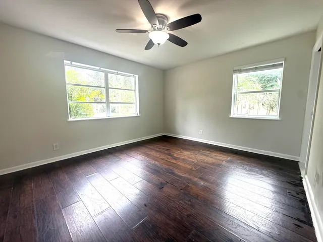 a view of an empty room with wooden floor and a window