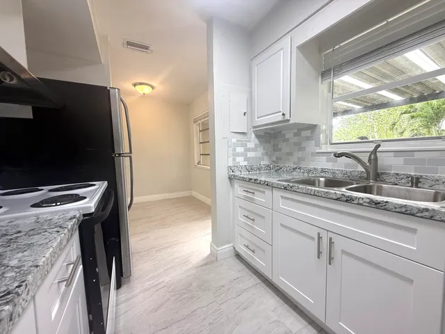 a kitchen with stainless steel appliances kitchen island granite countertop a sink stove and refrigerator