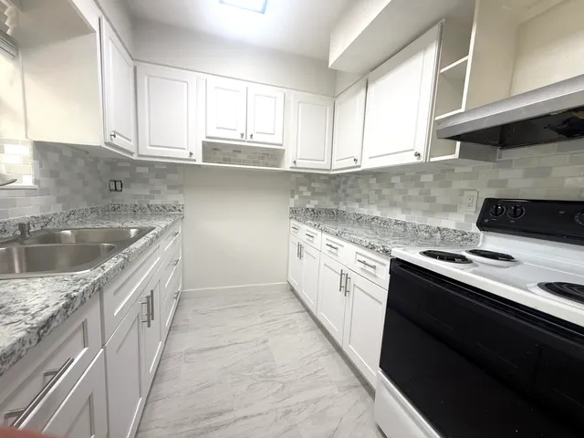 a kitchen with stainless steel appliances granite countertop a sink stove and cabinets