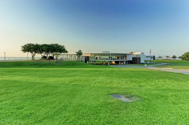 a view of a green field with lawn chairs and trees