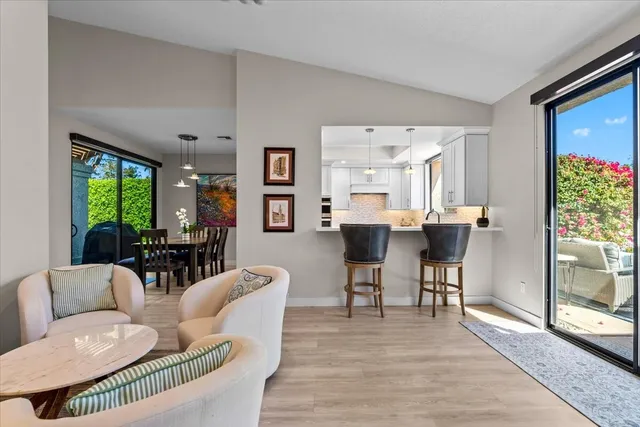 a living room with furniture potted plant floor to ceiling windows and a flat screen tv