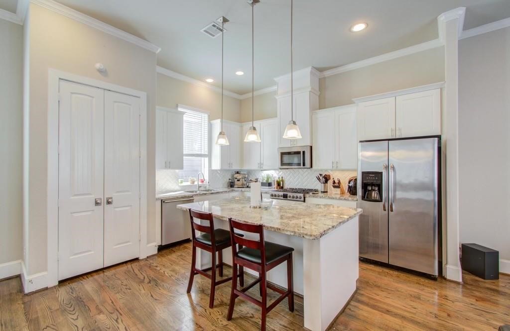 243 West 27th Street Houston, TX 77008 - Photo 11 of 31 a kitchen with stainless steel appliances granite countertop a kitchen island a stove a refrigerator a sink a dining table and chairs with wooden floor