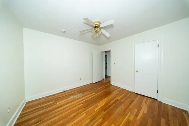 a view of a room with a ceiling fan and wooden floor