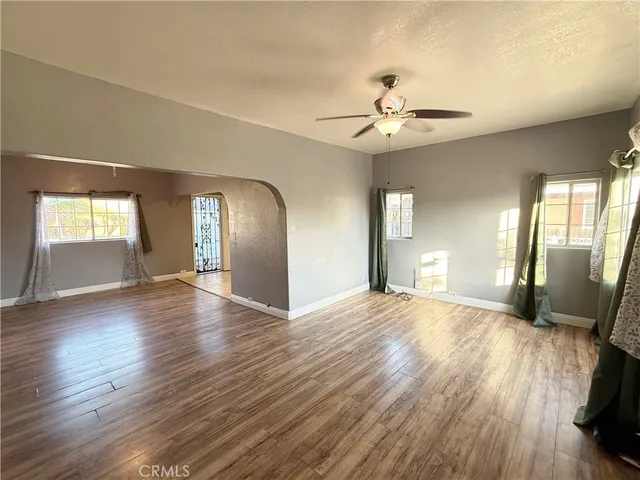 a view of an empty room with window and wooden floor