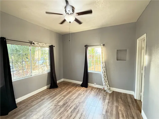 a view of empty room with wooden floor and fan