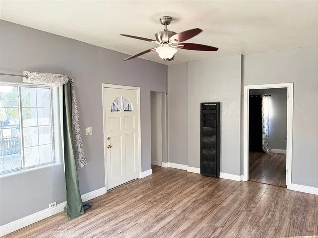 a view of an empty room with wooden floor and a window