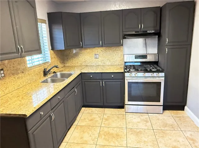 a kitchen with granite countertop a stove sink and cabinets