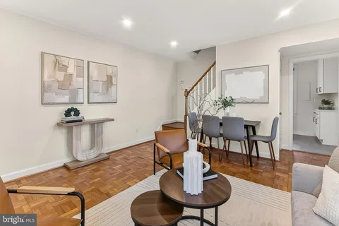 a living room with couches chairs and kitchen view with wooden floor