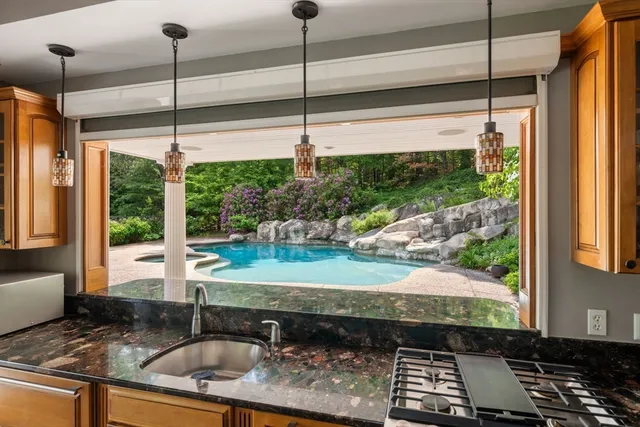 a kitchen with stainless steel appliances kitchen island granite countertop a stove a sink a refrigerator and white cabinets with wooden floor