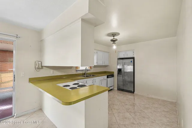 a kitchen with a refrigerator a stove cabinets and living room view