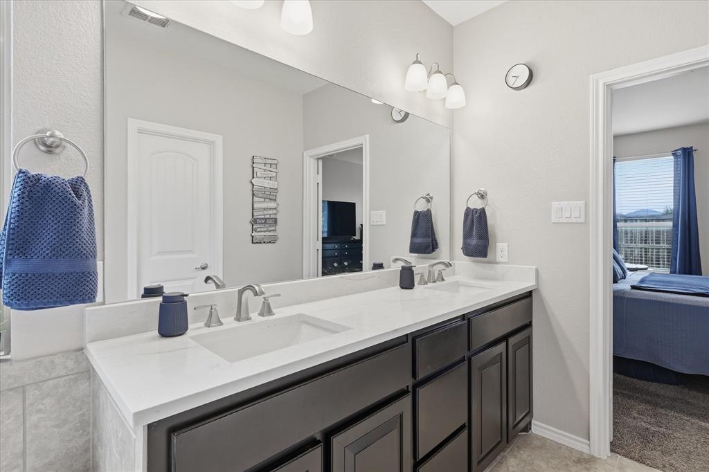 11500 Starlight Ranch Fort Worth, TX 76052 - Photo 23 of 40 Bathroom featuring a double vanity with dark cabinetry, white countertops, and integrated sinks
