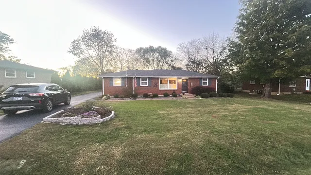 a front view of a house with a garden and trees