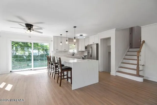 a kitchen with stainless steel appliances a dining table chairs and wooden floor
