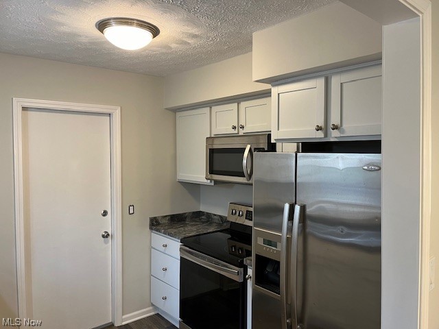 3052 Bancroft Road Akron, OH 44333 - Photo 5 of 11 Kitchen featuring white cabinets, appliances with stainless steel finishes, dark stone countertops, and a textured ceiling