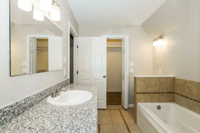 a bathroom with a tub sink and mirror