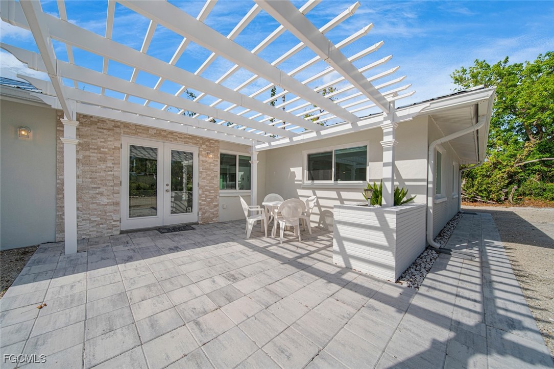 4639 Brainard Bayou Road Sanibel, FL 33957 - Photo 41 of 50 a view of a patio with table and chairs potted plants and floor to ceiling window