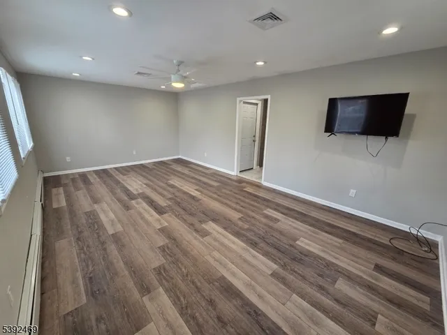 a view of empty room with wooden floor
