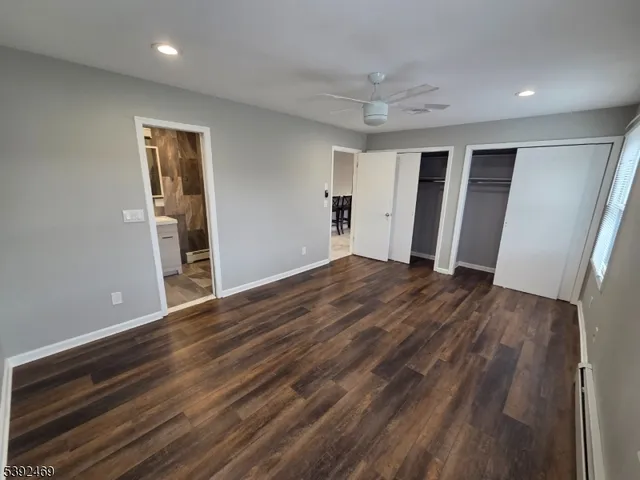 a view of an empty room with wooden floor and closet
