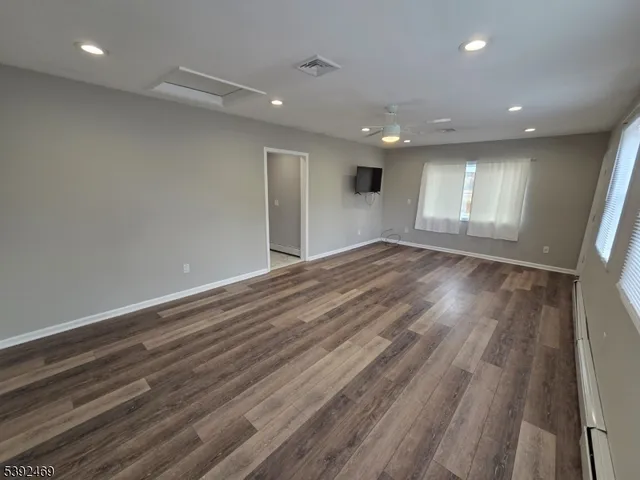 an empty room with wooden floor and windows