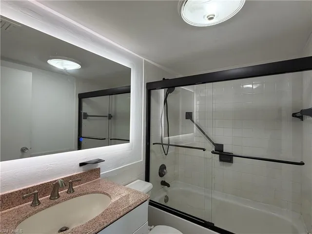 a bathroom with a granite countertop sink a mirror and shower