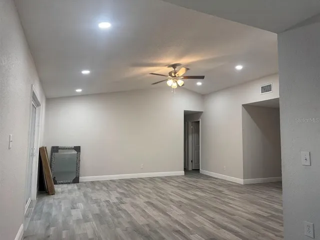 a view of an empty room with wooden floor and chandelier