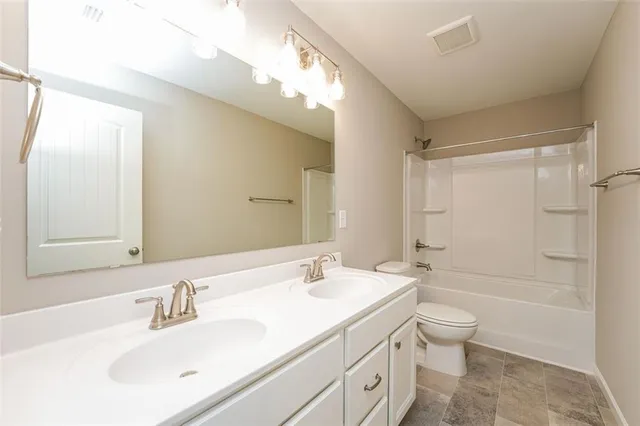 a bathroom with a granite countertop sink a toilet and shower