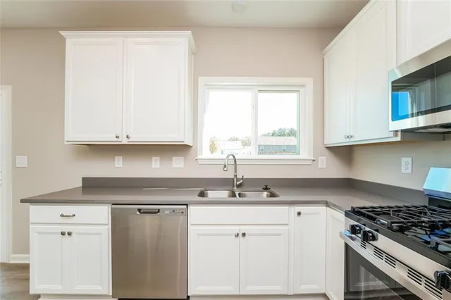 a kitchen with stainless steel appliances granite countertop white cabinets and a stove top oven