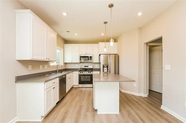 a large kitchen with stainless steel appliances kitchen island granite countertop a stove a refrigerator a sink and a microwave with wooden floor