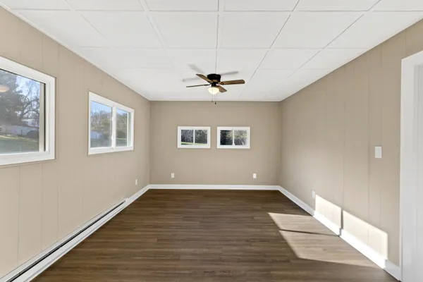 a view of an empty room with window and wooden floor
