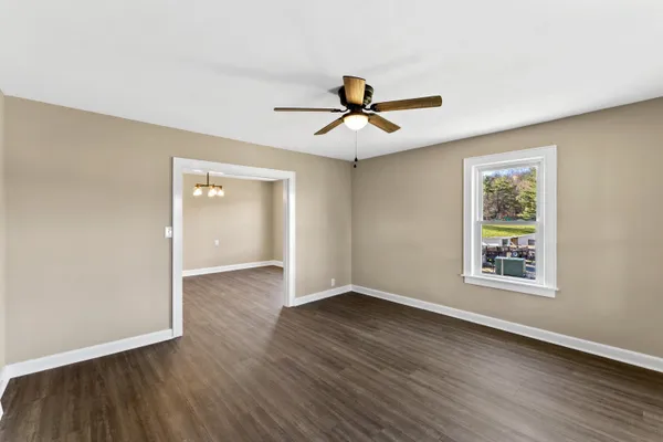 a view of an empty room with wooden floor and a window